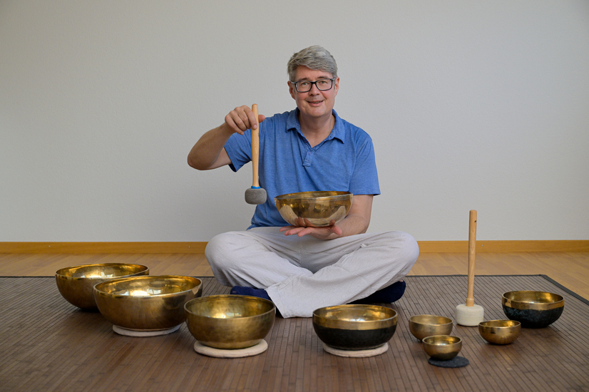Klangmassagen von Mitklang in Kriens mit Charly Locher. Charly Locher, Inhaber von Mitklang, spielt eine Klangschale an.